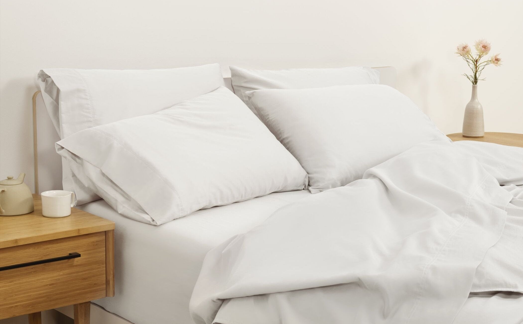Fully dressed bed with white sheets and nightstands on either side