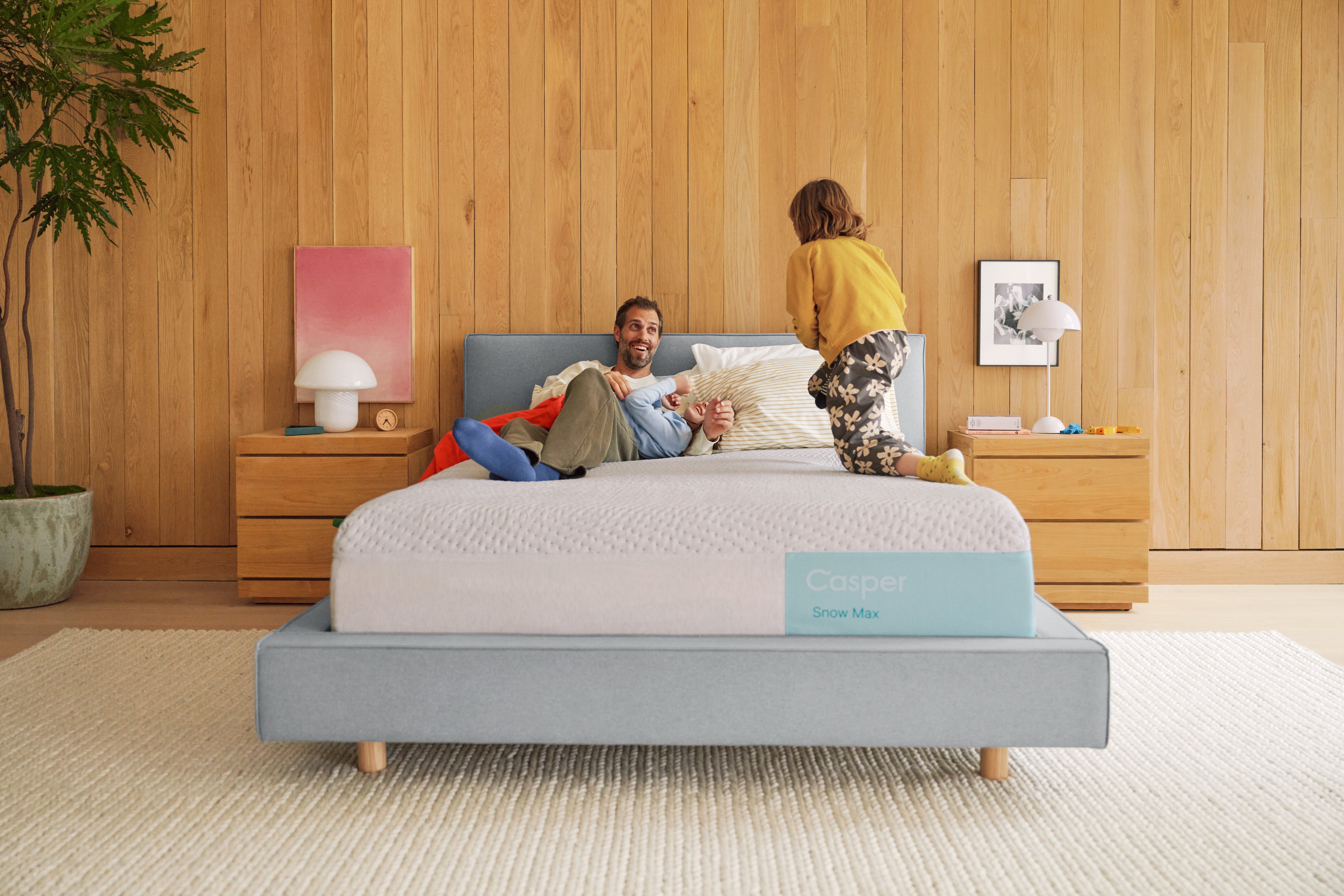 A father and his children play together in bed.