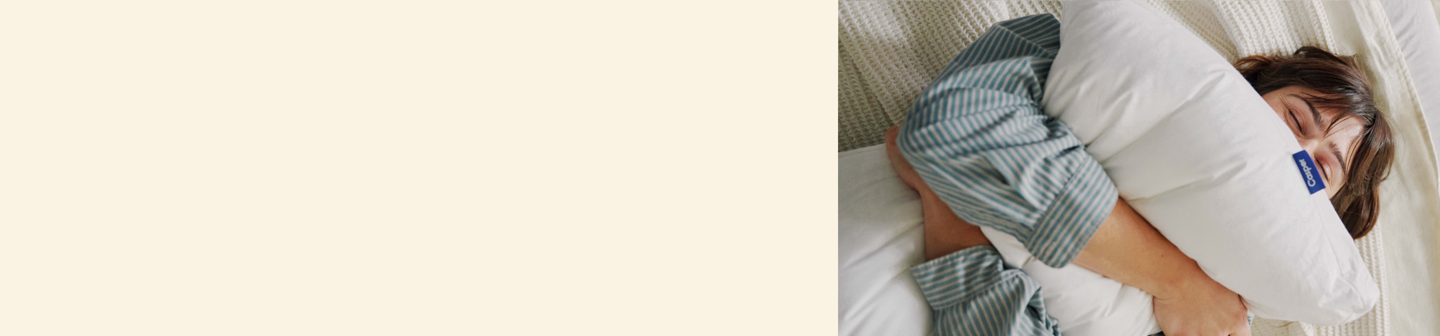 Beige background. Image of a woman squeezing a pillow in bed.