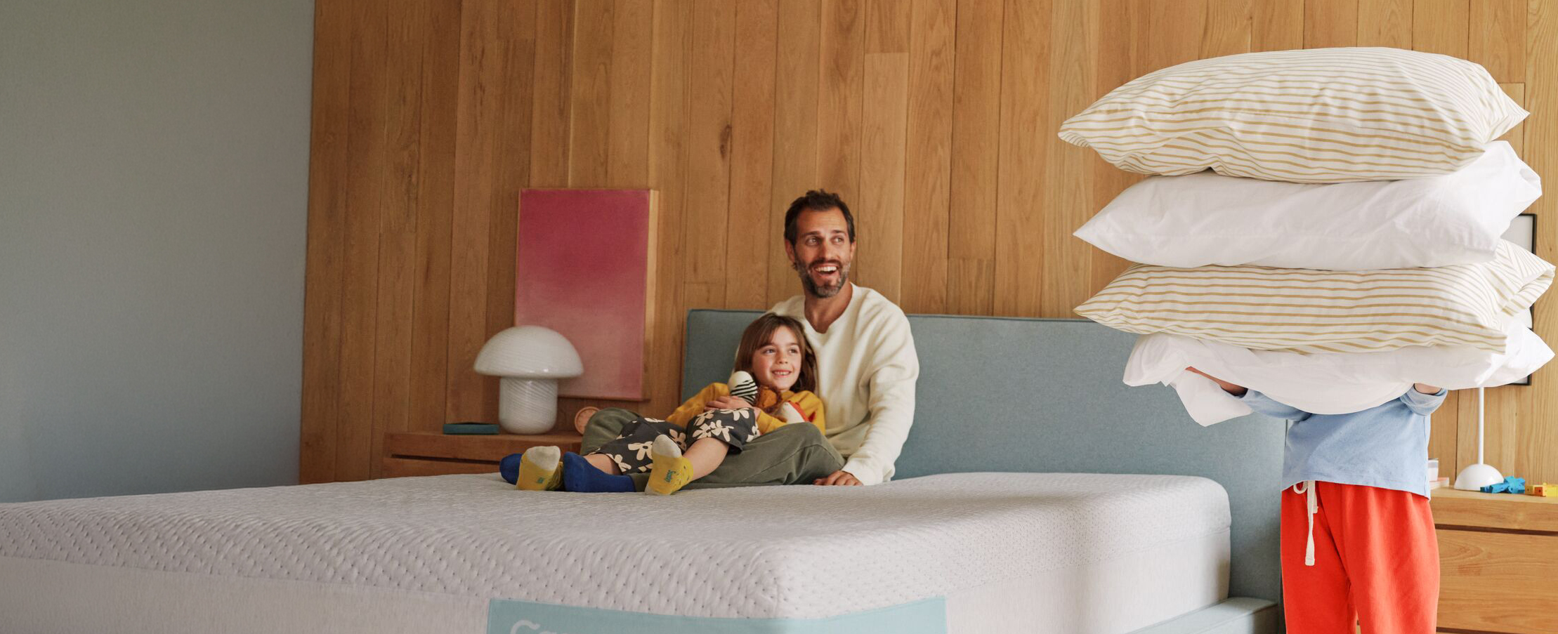 Man and child with a mattress and pillows in a bedroom setting