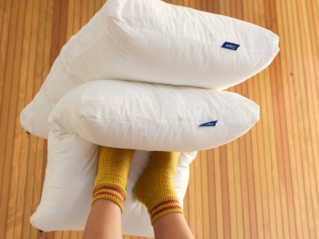 Two white Casper pillows held by a person wearing yellow socks