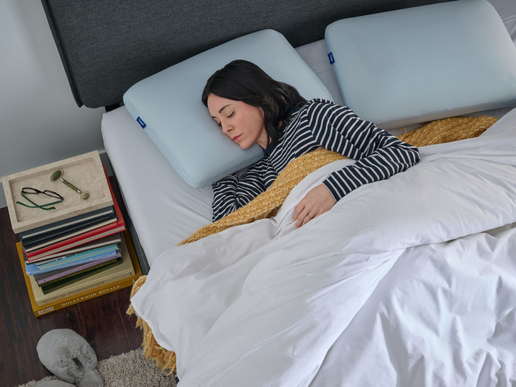 Woman sleeping on a bed with a light blue colored pillow and a white comforter