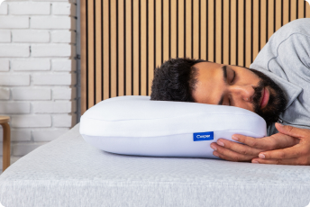 A man sleeps on his side on a pillow.