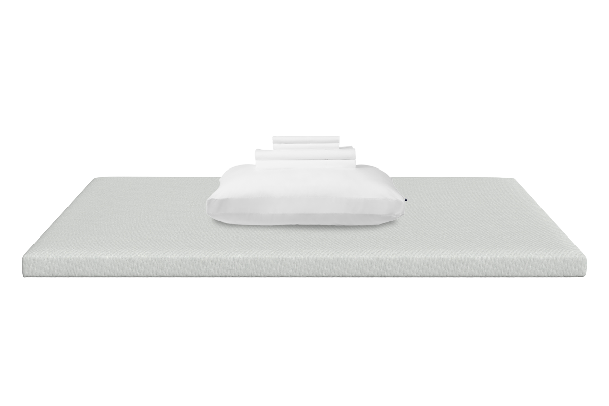 A white textured mattress topper with a pillow and folded white sheets on stacked on top of it