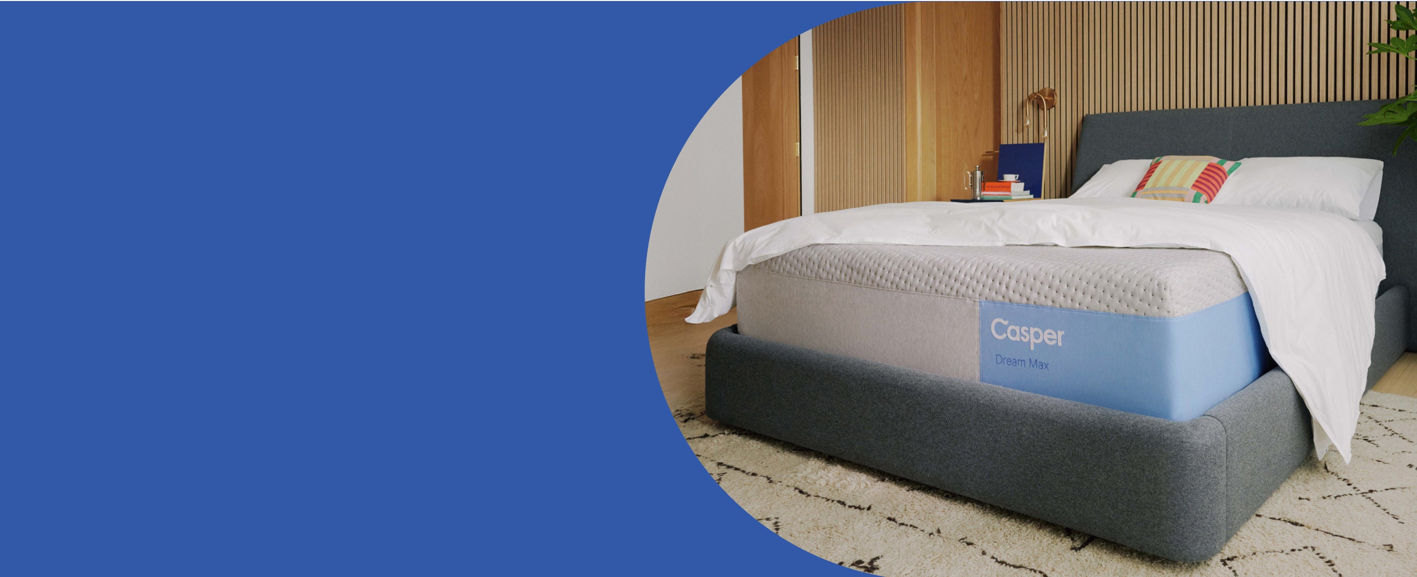 A Casper Dream Mattress on a bed frame with a blanket and pillows on top
