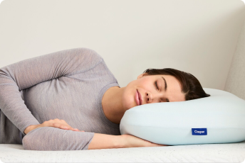A woman sleeps on her side on a Hybrid Snow Pillow.